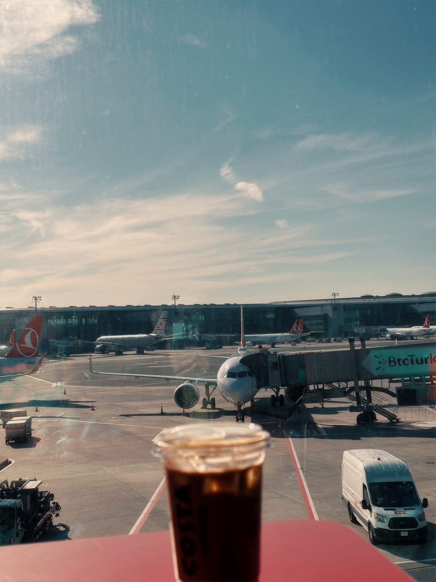 Iced coffee by the window at Istanbul Airport, planes at the gates