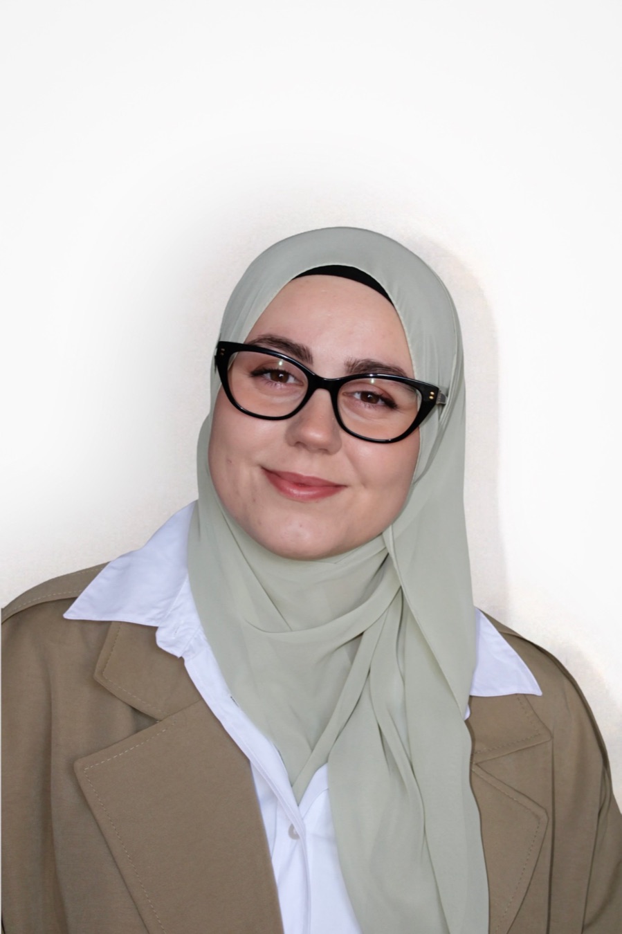 Portrait of Zejneba smiling, in glasses and a beige blazer