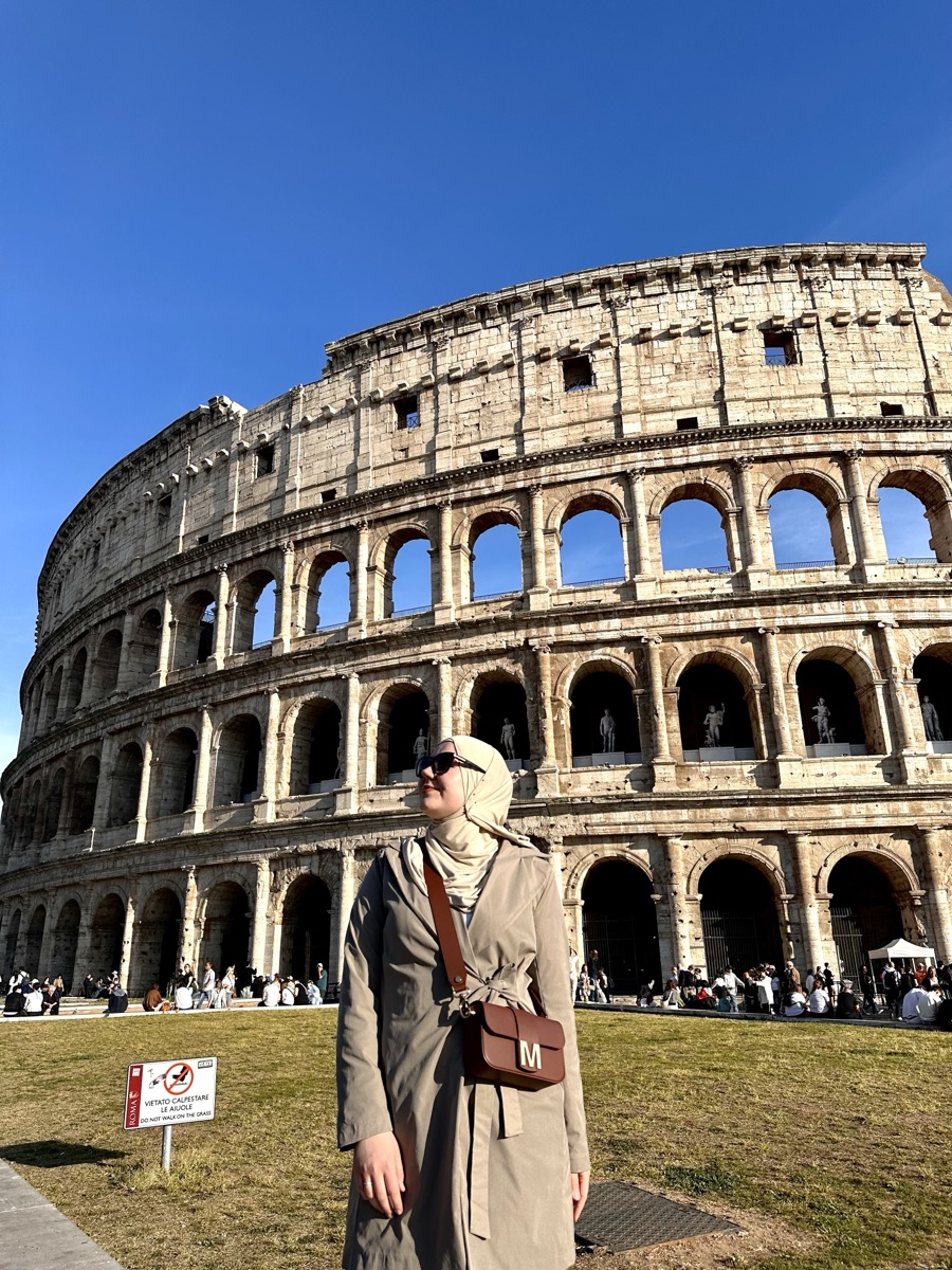 Zejneba standing in front of the Colosseum in Rome on a sunny day